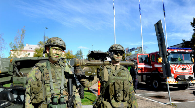 Kaksi varusmiestä kasvomaskeissa ja varusteissa ulkona kaupungintalon pihalla